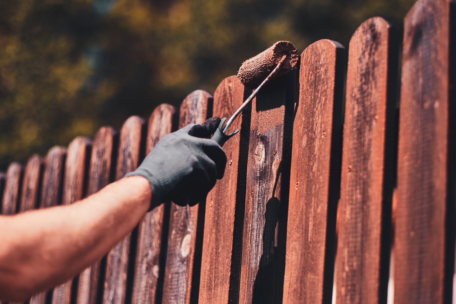 diligent man is painting fence with brush scaled